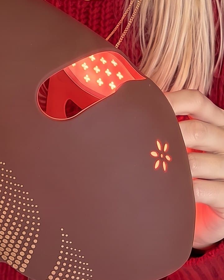 The Albelys mask held in two hands, switched on, its grid of red LEDs glowing inside