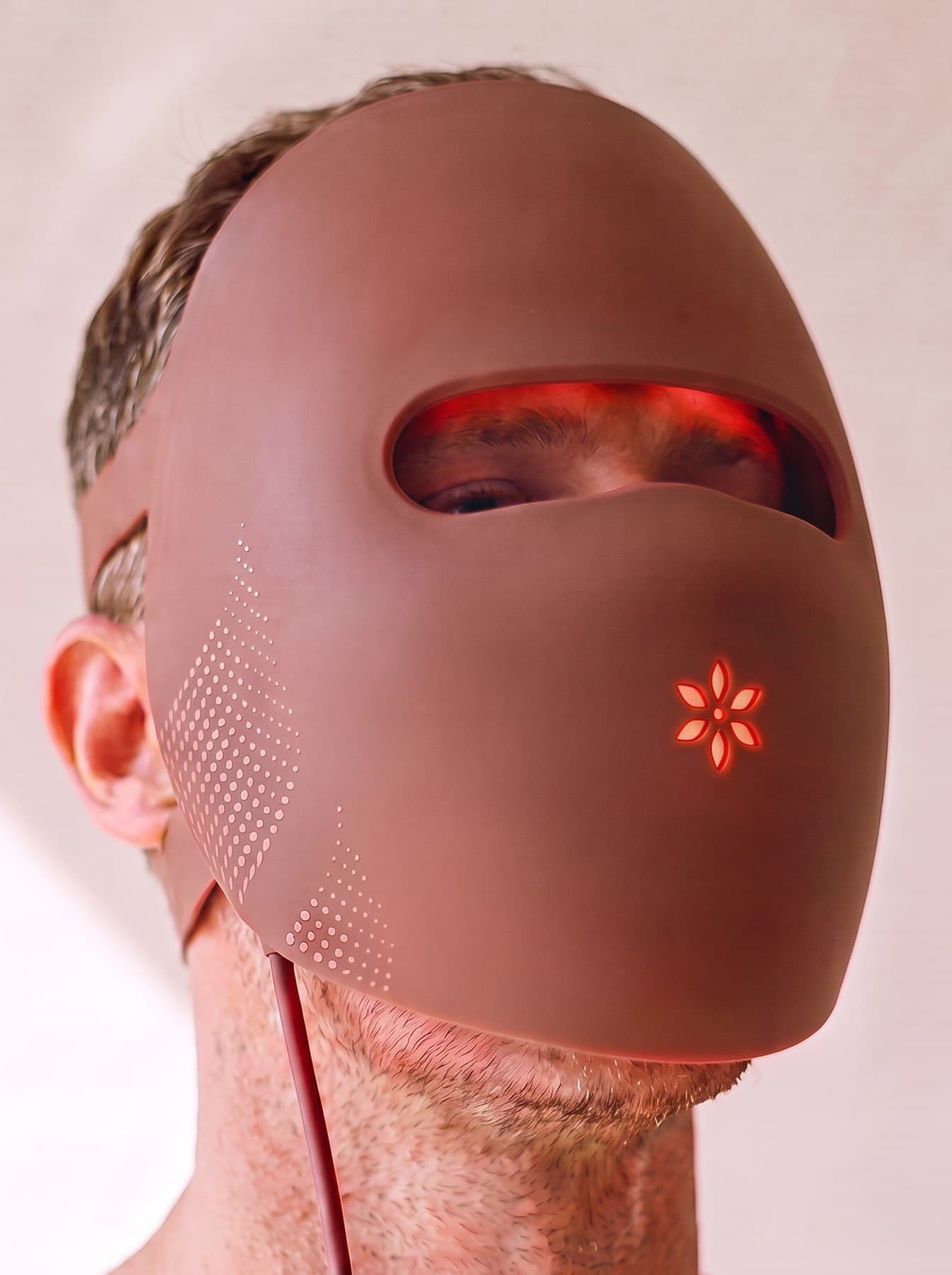 Close portrait of a man wearing the Albelys mask against a plain wall