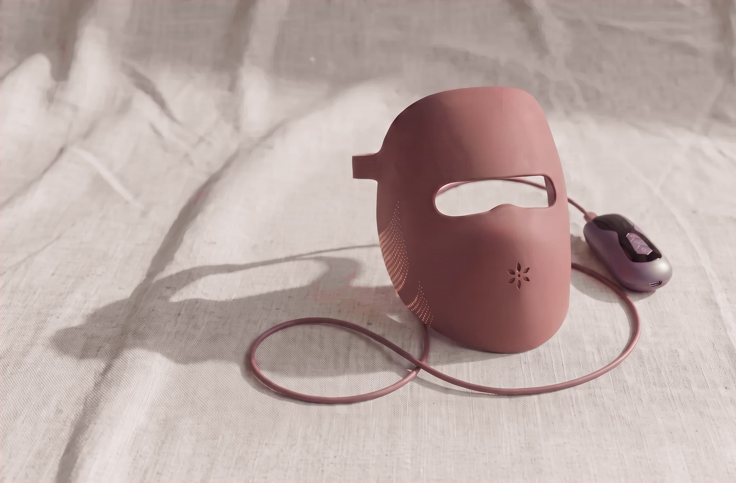 The Albelys silicone LED mask standing upright on natural linen, its cord and inline controller beside it in soft morning light
