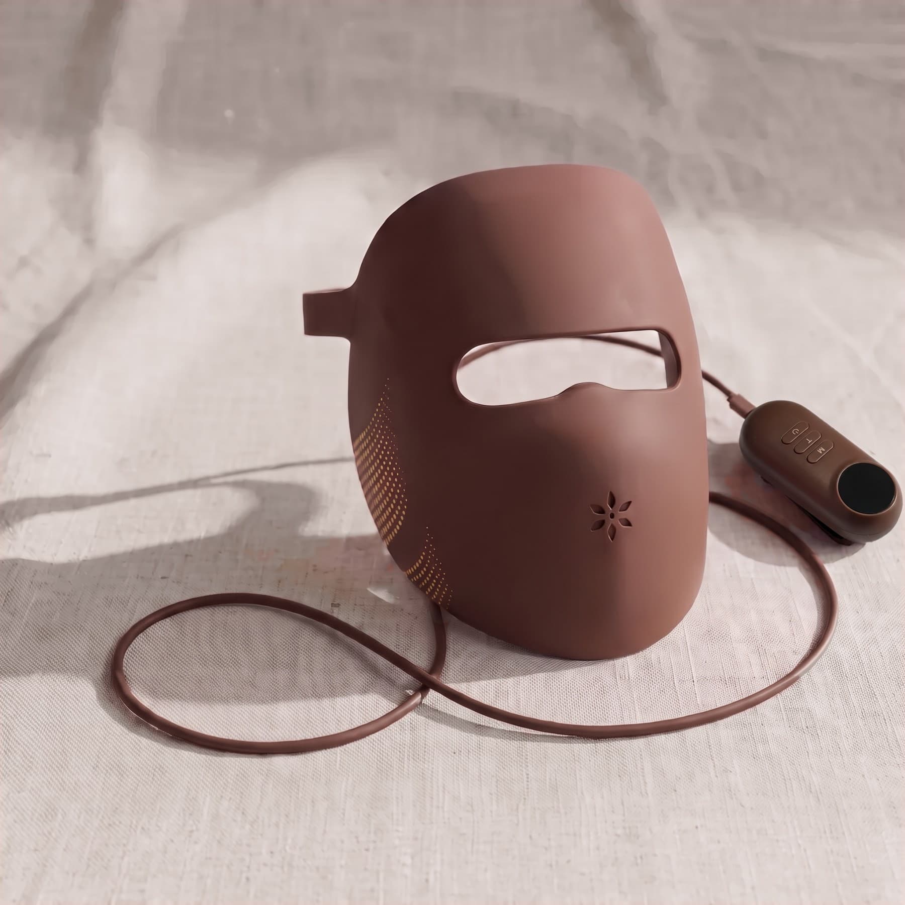 The Albelys silicone LED mask on linen, with its cable and controller