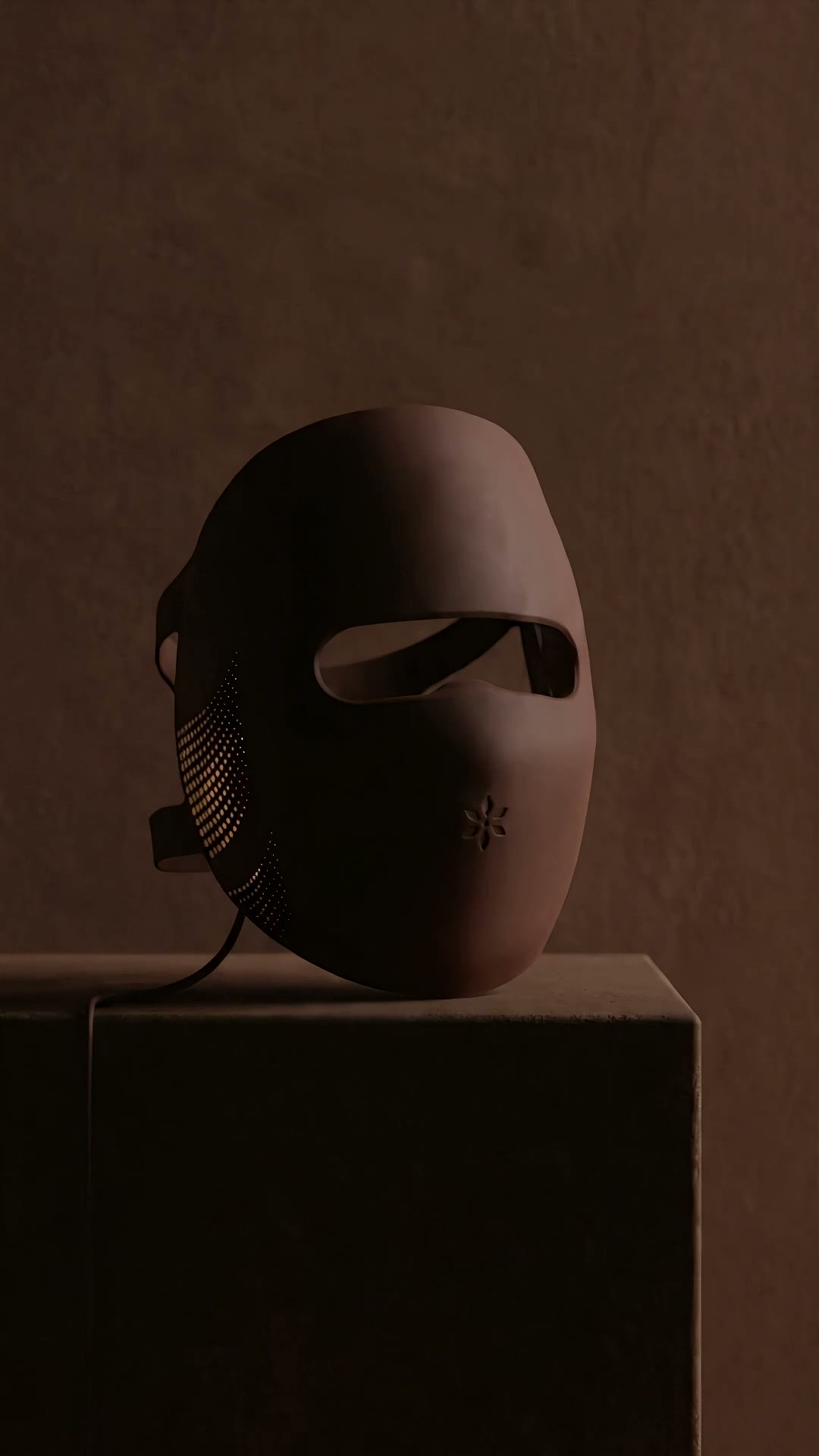 The Albelys silicone LED mask on a dark plinth switches on: red light glows through the eye opening as the camera circles it