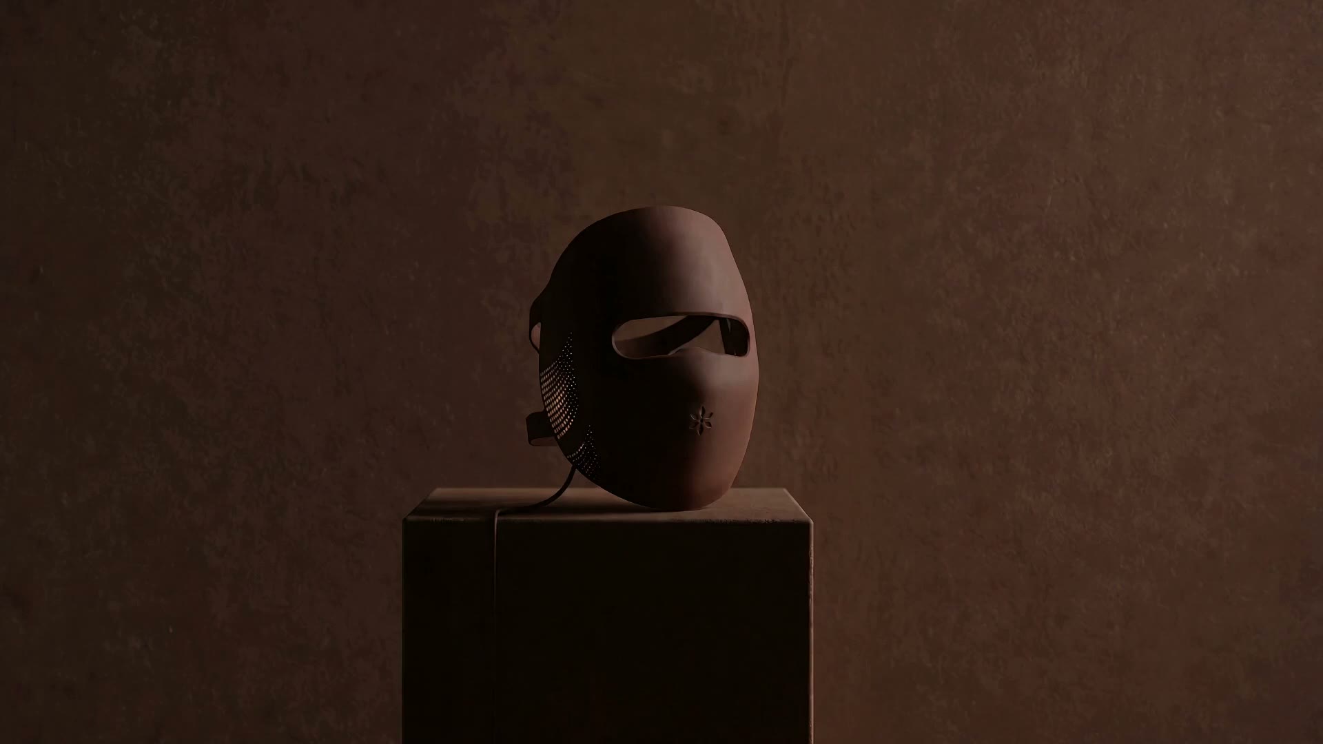 The Albelys silicone LED mask on a dark plinth switches on: red light glows through the eye opening as the camera circles it